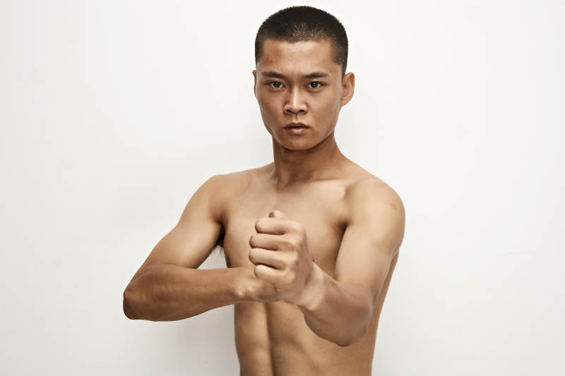 白色背景下演示自由搏击动作的亚洲功夫男性图片