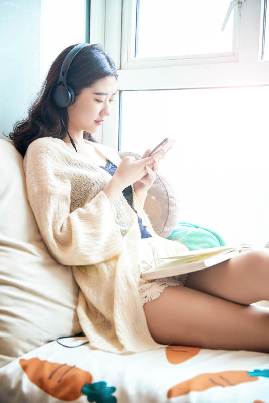 躺在舒适的飘窗上听音乐看书玩手机的女孩图片