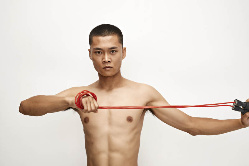 白色背景下手持运动跳绳的亚洲健身男士形象图片