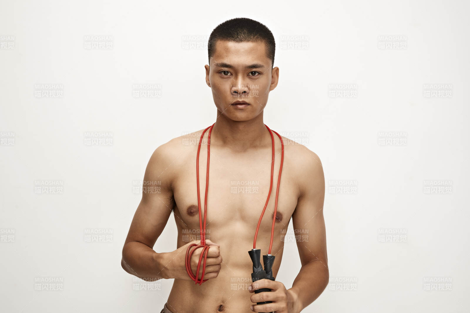 白色背景下手持运动跳绳的亚洲健身男士形象图片