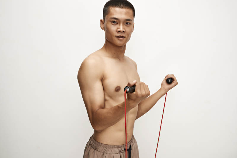 白色背景下手持运动跳绳的亚洲健身男士形象图片