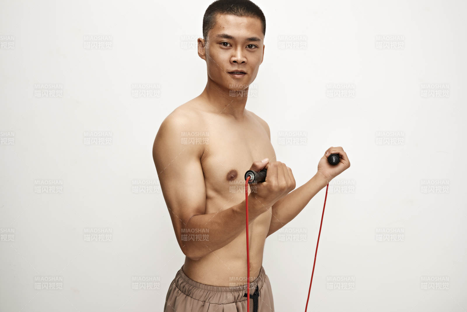 白色背景下手持运动跳绳的亚洲健身男士形象图片