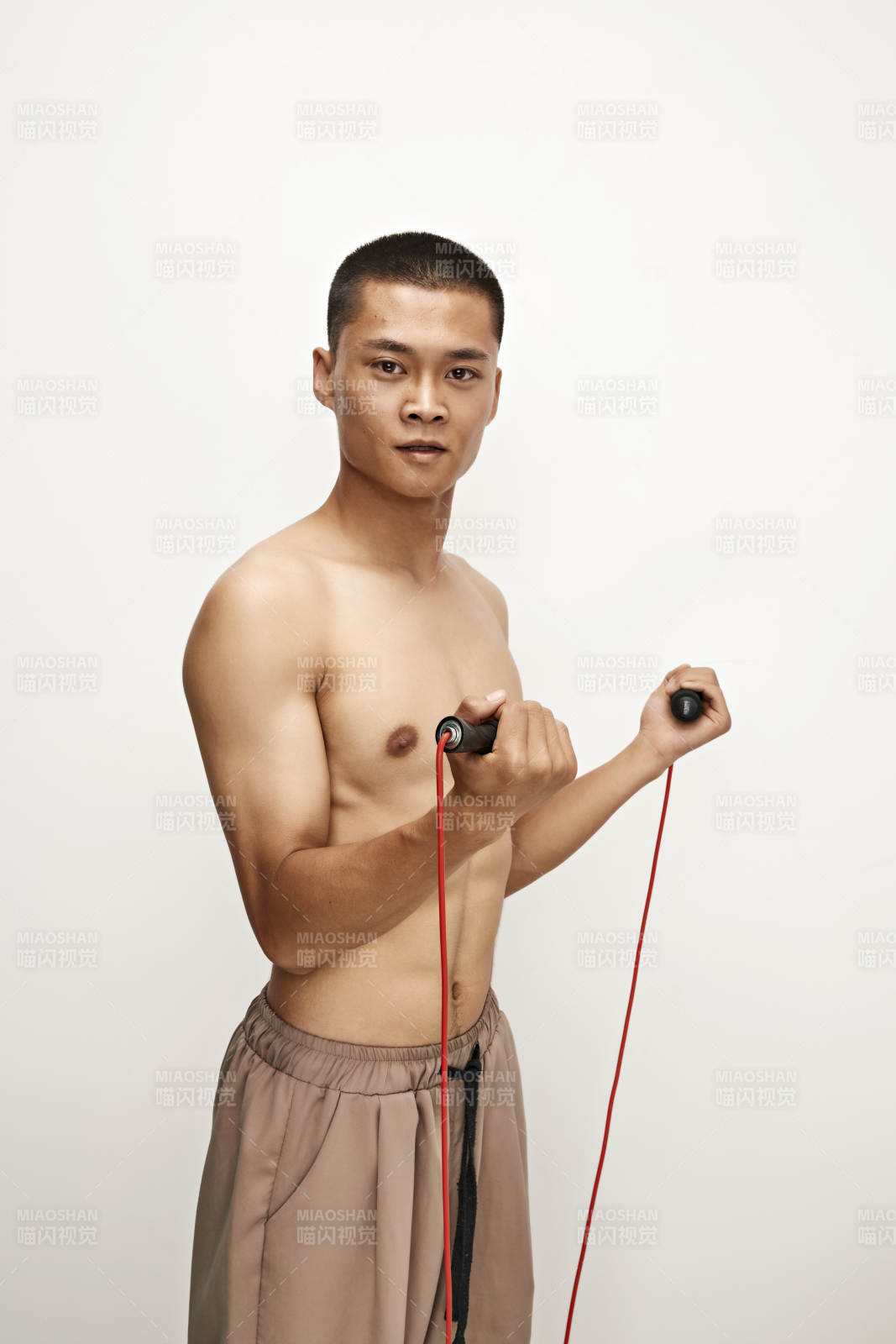 白色背景下手持运动跳绳的亚洲健身男士形象图片