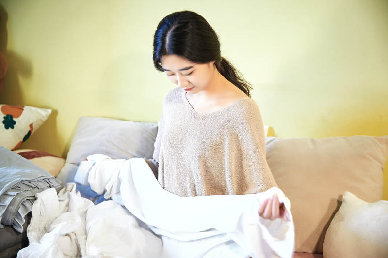 在沙发床上整理行装的年轻亚洲女性图片