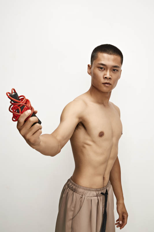 白色背景下手持运动跳绳的亚洲健身男士形象图片