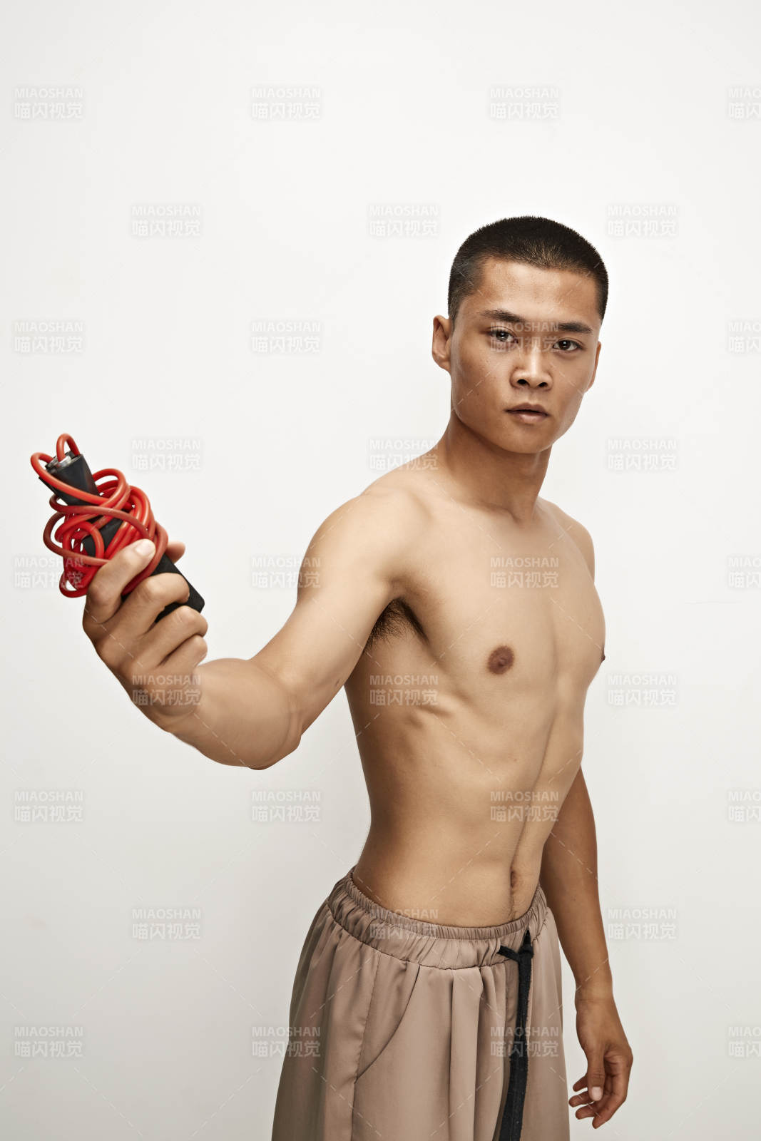 白色背景下手持运动跳绳的亚洲健身男士形象图片