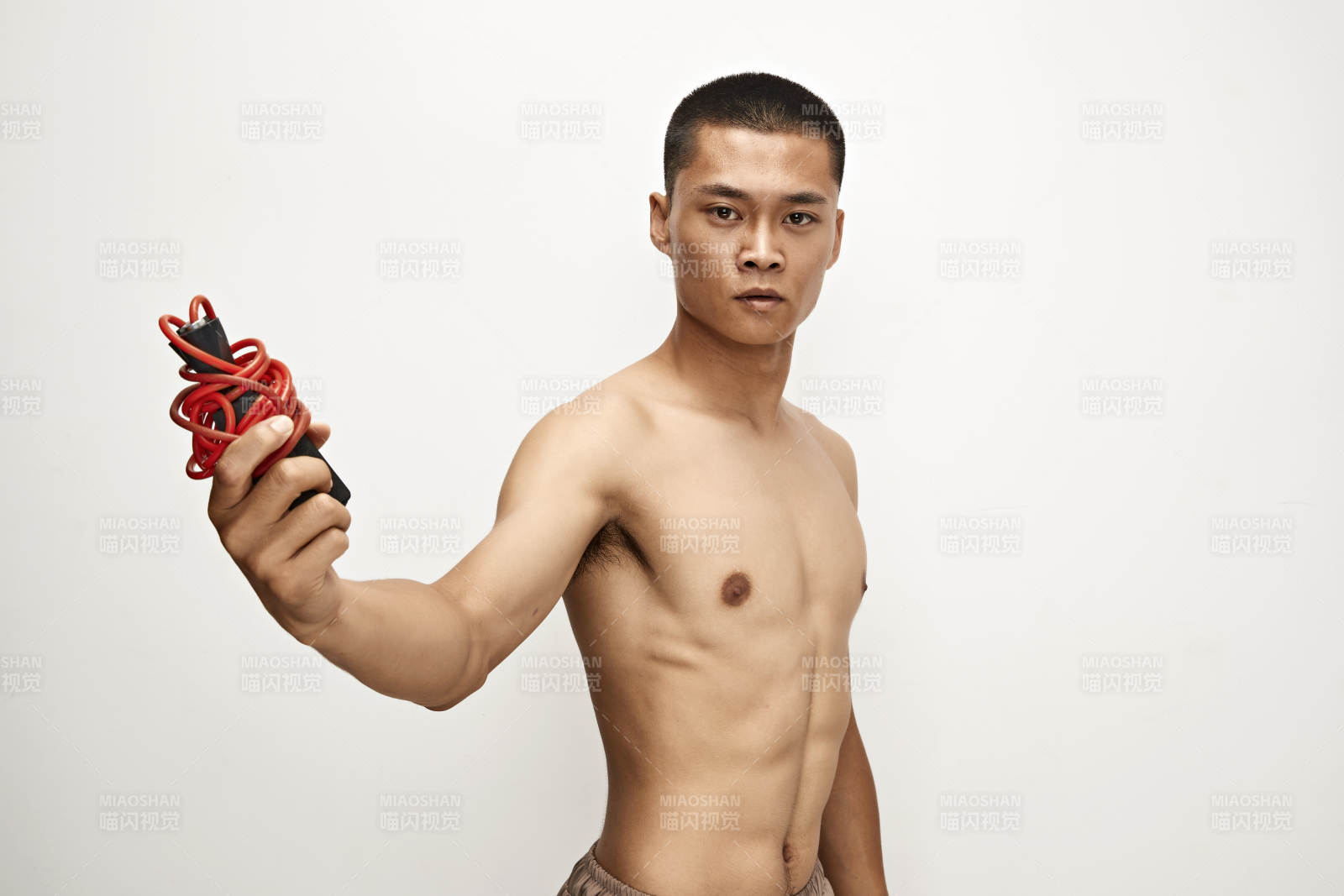 白色背景下手持运动跳绳的亚洲健身男士形象图片