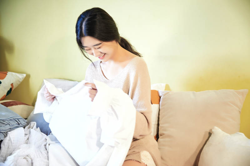 在沙发床上整理行装的年轻亚洲女性图片