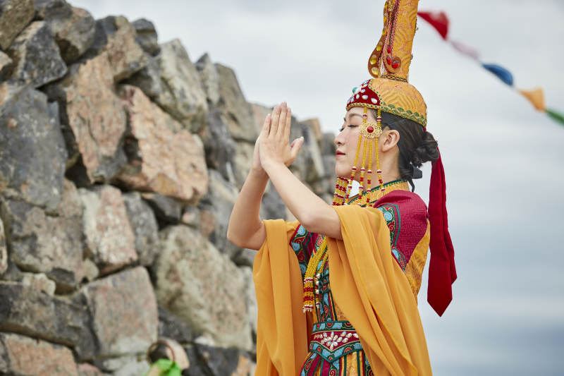 草原上敖包前身穿豪华蒙古族服饰的蒙族少女图片