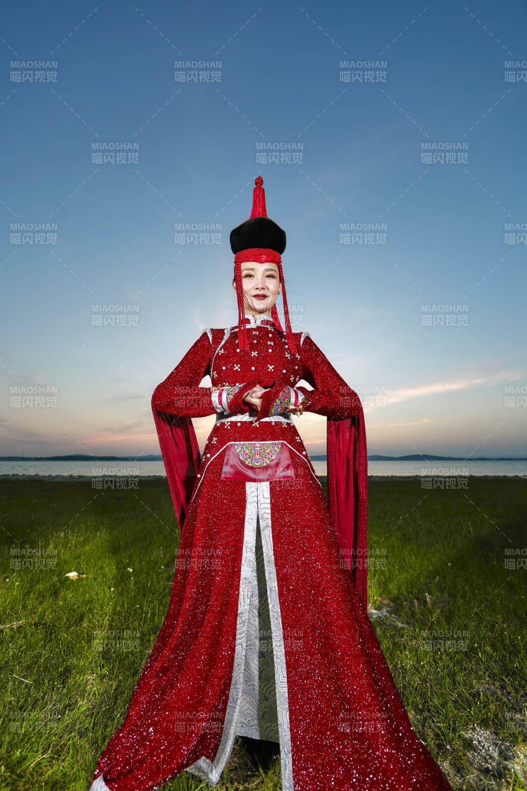 晚霞的草原湖畔穿蒙古族传统服饰的年轻女性图片