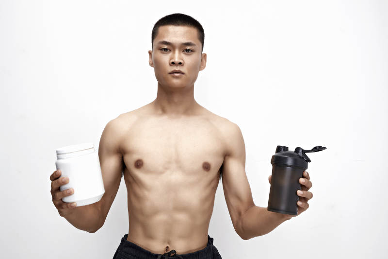 手持蛋白粉的身材匀称肌肉扎实的亚洲男性图片