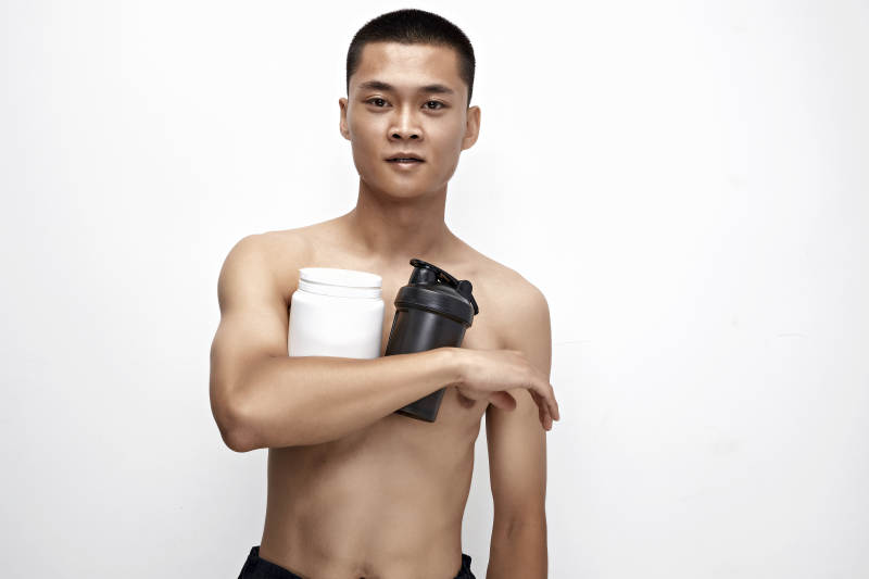 手持蛋白粉的身材匀称肌肉扎实的亚洲男性图片