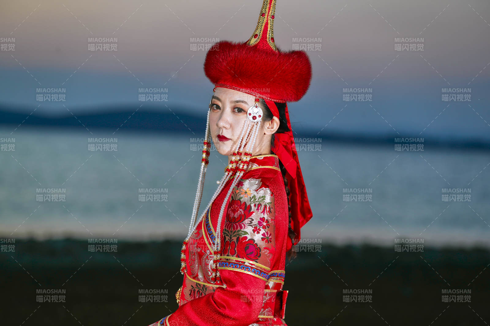 晚霞的草原湖畔穿蒙古族传统服饰的年轻女性图片