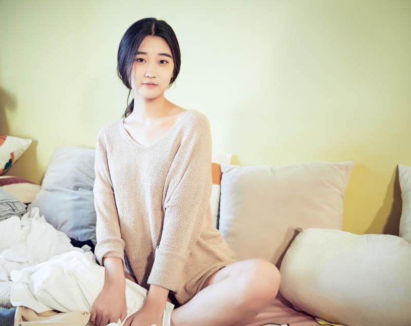 在沙发床上整理行装的年轻亚洲女性图片