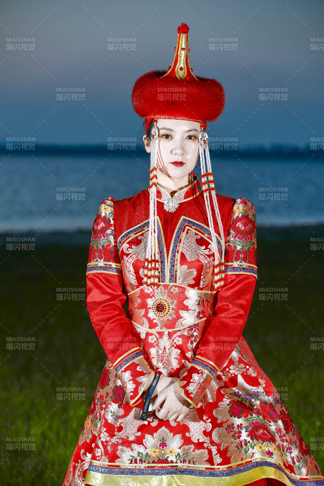 晚霞的草原湖畔穿蒙古族传统服饰的年轻女性图片