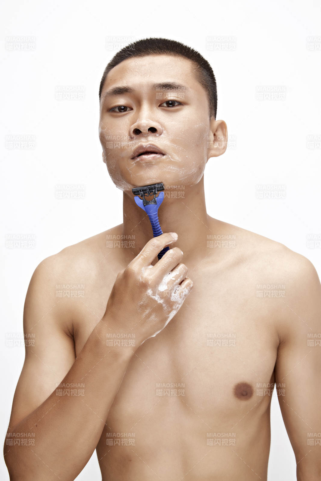 白色背景下手持剃须刀在刮胡子的亚洲男性图片
