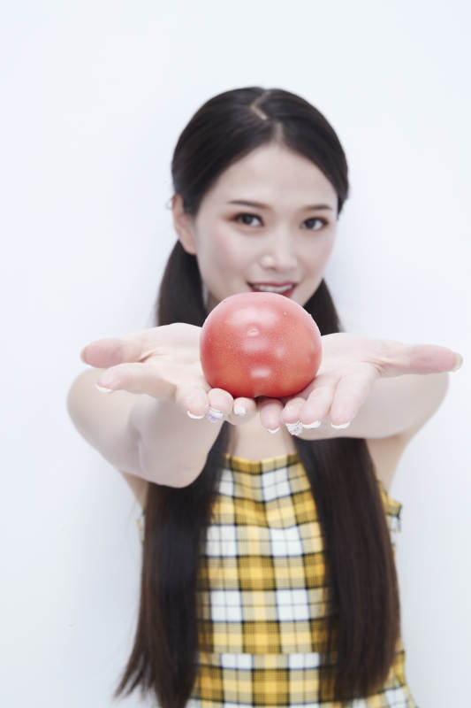 啃咬番茄身穿格子吊带裙的亚洲可爱少女人像图片