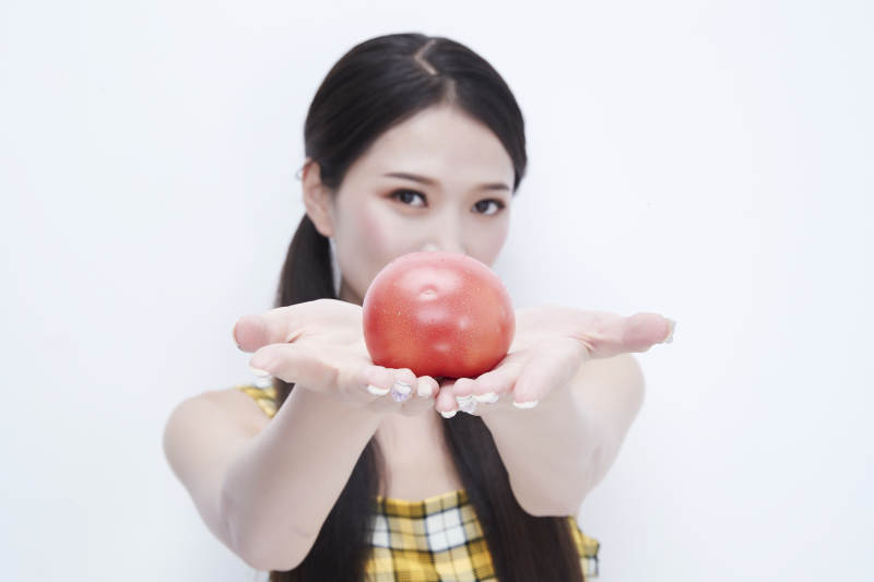 啃咬番茄身穿格子吊带裙的亚洲可爱少女人像图片