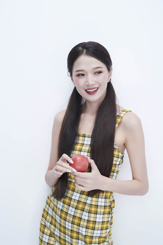 啃咬番茄身穿格子吊带裙的亚洲可爱少女人像图片