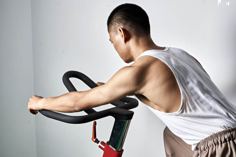 在室内进行动感单车锻炼的亚洲健身男士形象图片