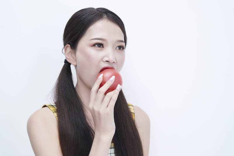啃咬番茄身穿格子吊带裙的亚洲可爱少女人像图片