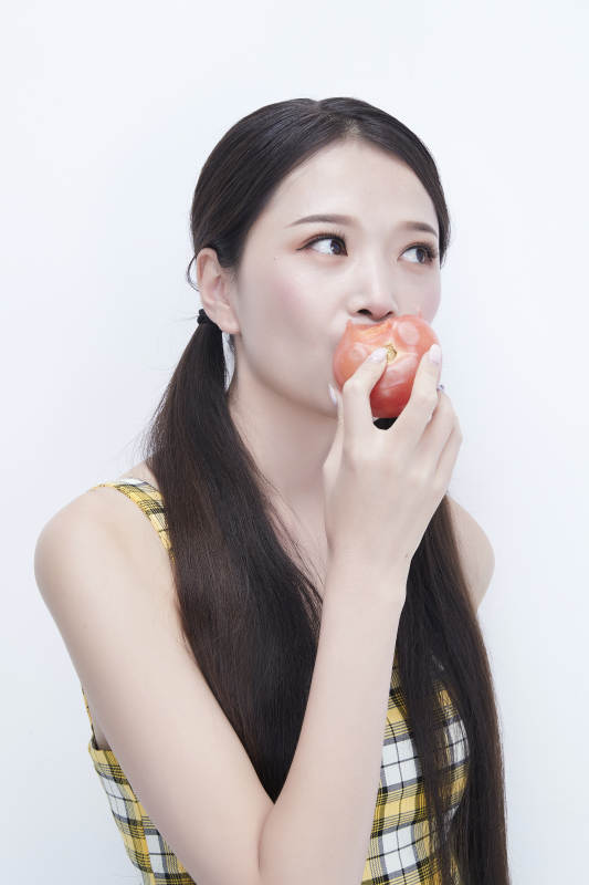 啃咬番茄身穿格子吊带裙的亚洲可爱少女人像图片