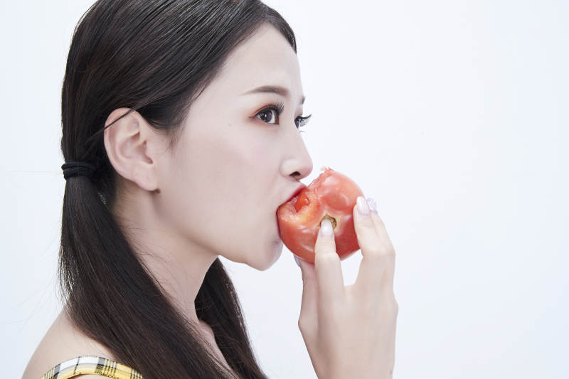 啃咬番茄身穿格子吊带裙的亚洲可爱少女人像图片