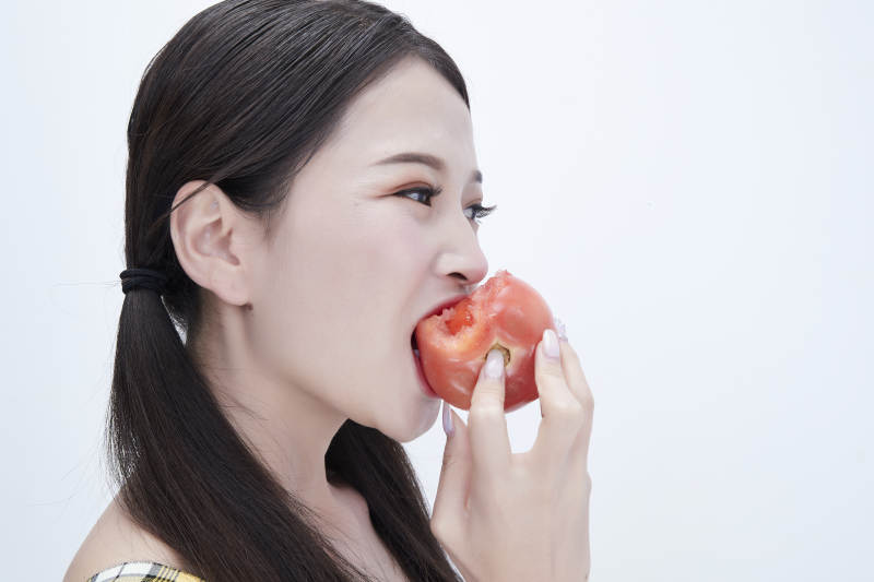 啃咬番茄身穿格子吊带裙的亚洲可爱少女人像图片