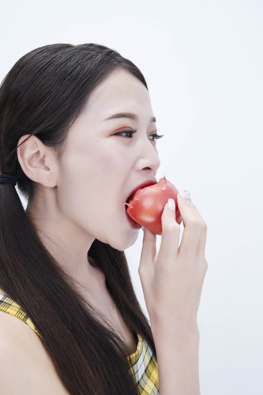 啃咬番茄身穿格子吊带裙的亚洲可爱少女人像图片