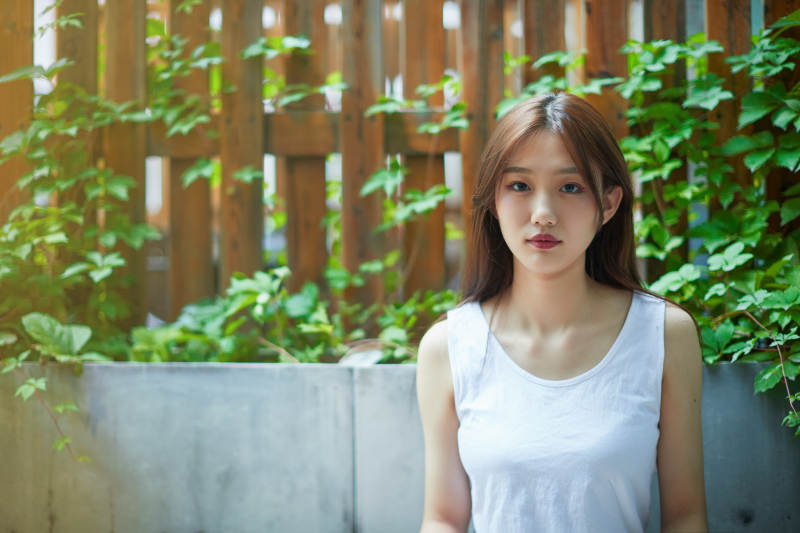 院子里坐在长椅上阅读书籍的亚洲长发少女图片