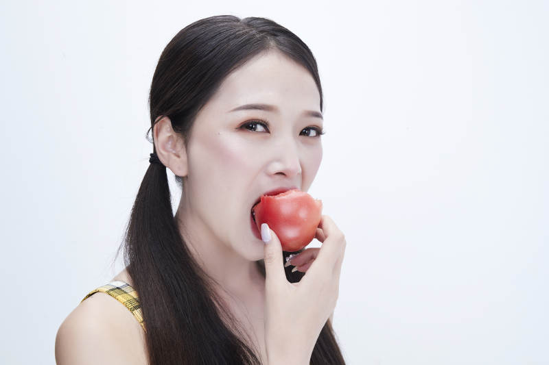 啃咬番茄身穿格子吊带裙的亚洲可爱少女人像图片