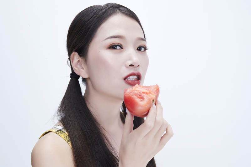 啃咬番茄身穿格子吊带裙的亚洲可爱少女人像图片