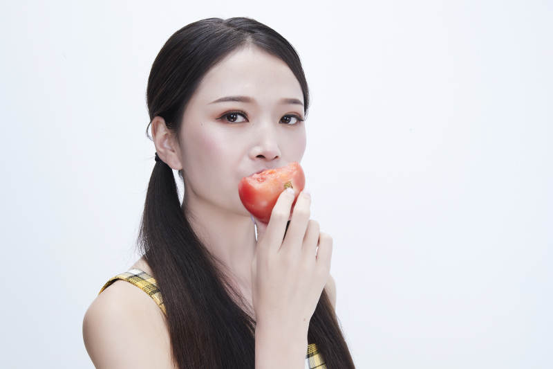 啃咬番茄身穿格子吊带裙的亚洲可爱少女人像图片