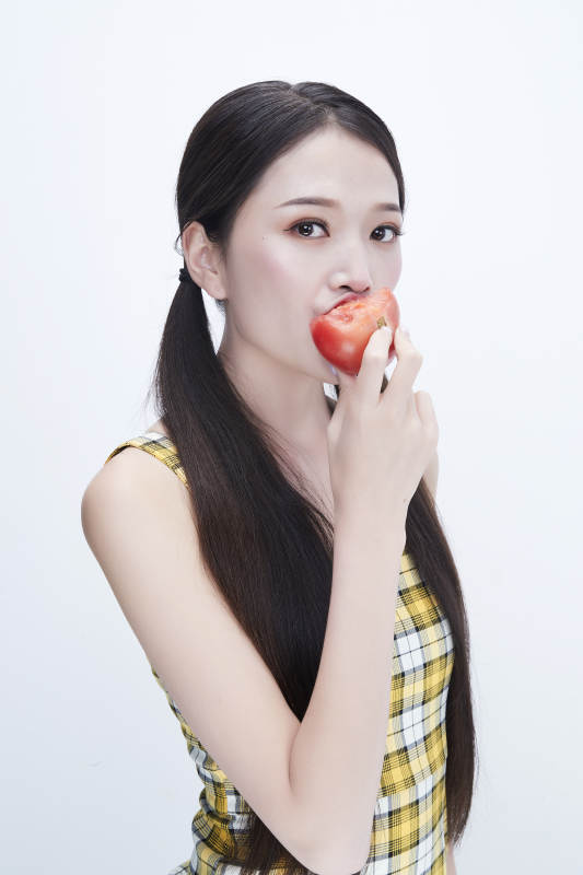 啃咬番茄身穿格子吊带裙的亚洲可爱少女人像图片