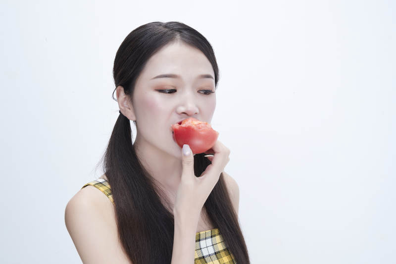 啃咬番茄身穿格子吊带裙的亚洲可爱少女人像图片