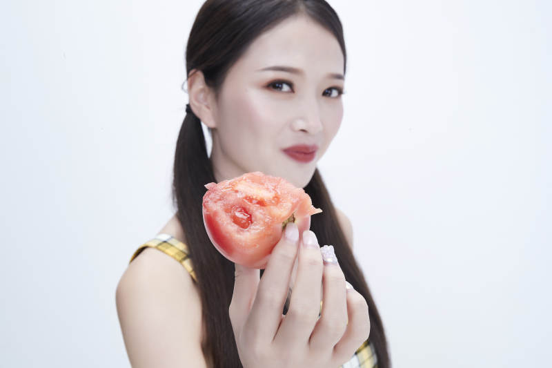 啃咬番茄身穿格子吊带裙的亚洲可爱少女人像图片