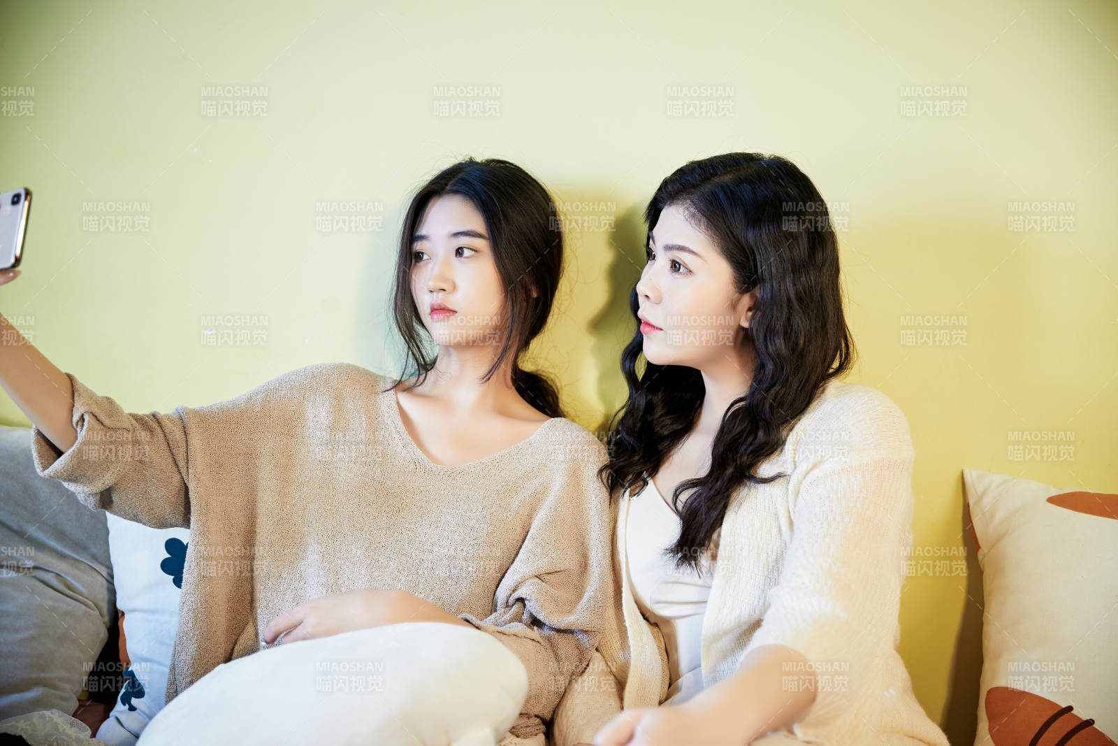 坐在床上玩手机的俩位美女图片