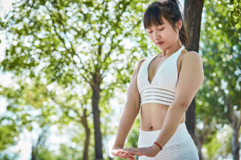 湖畔公园做瑜伽动作的亚洲年轻女性图片