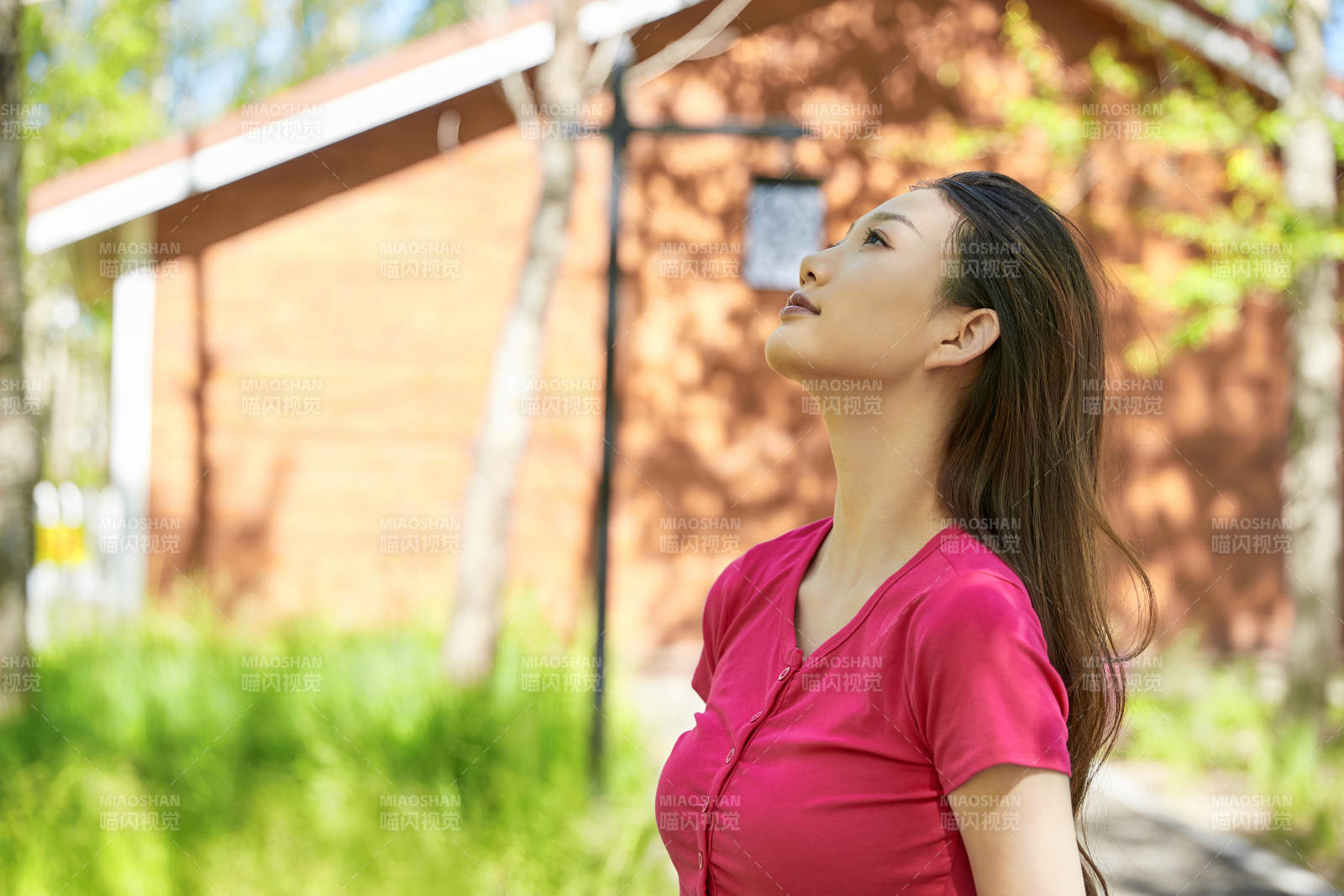 站在绿草如茵的木屋别墅群外的东方美女图片