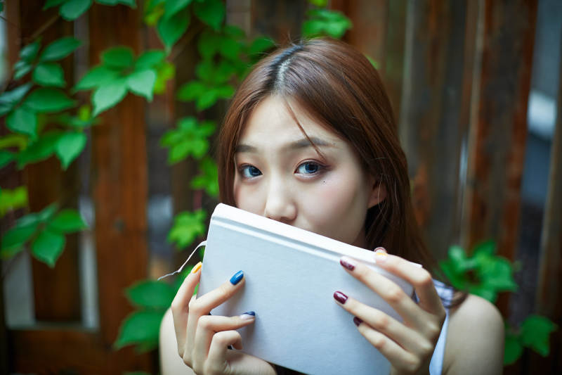 院子里坐在长椅上阅读书籍的亚洲长发少女图片