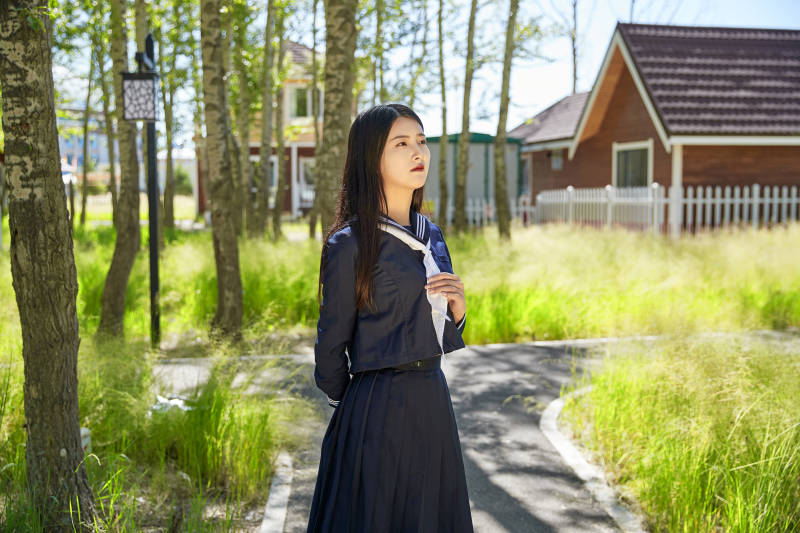 站在绿草如茵的木屋别墅群外的东方美女图片