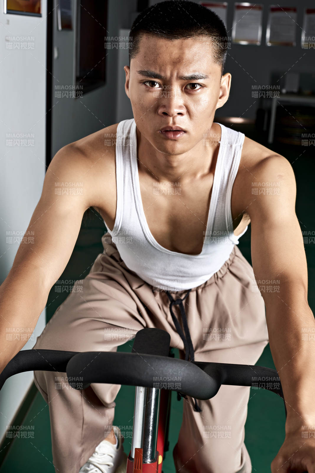 在室内进行动感单车锻炼的亚洲健身男士形象图片