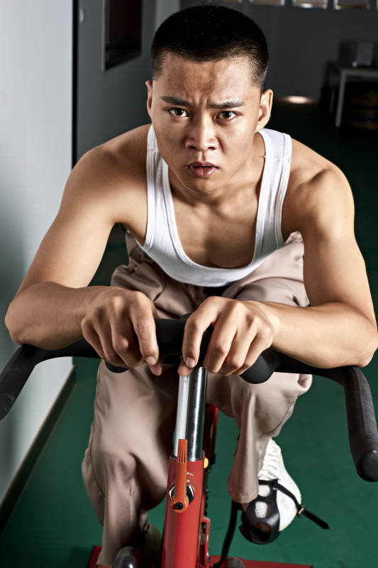 在室内进行动感单车锻炼的亚洲健身男士形象图片