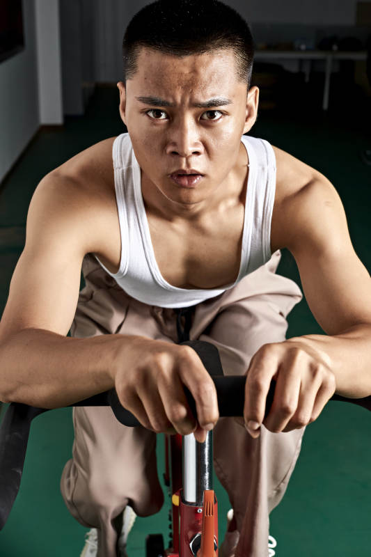 在室内进行动感单车锻炼的亚洲健身男士形象图片