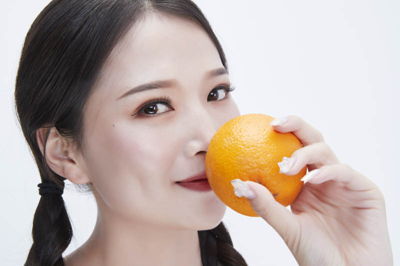 手拿橙子身穿镂空连衣裙的亚洲可爱少女人像图片