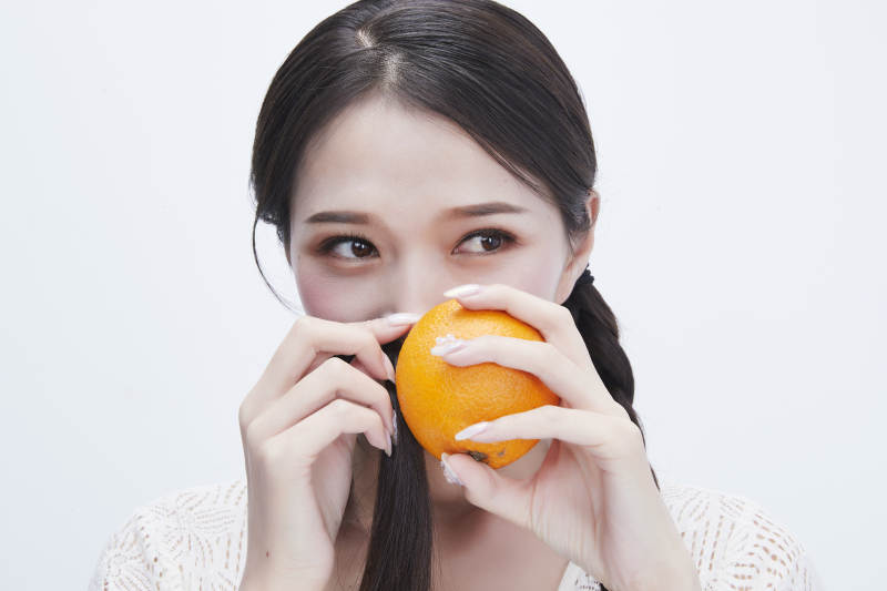 手拿橙子身穿镂空连衣裙的亚洲可爱少女人像图片