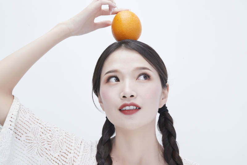 头顶橙子身穿镂空连衣裙的亚洲可爱少女人像图片