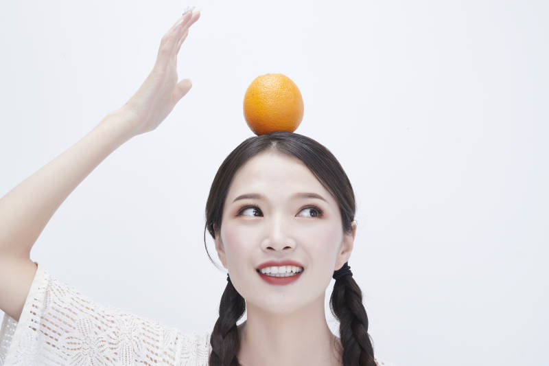 头顶橙子身穿镂空连衣裙的亚洲可爱少女人像图片