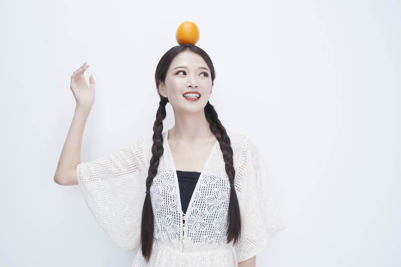 头顶橙子身穿镂空连衣裙的亚洲可爱少女人像图片