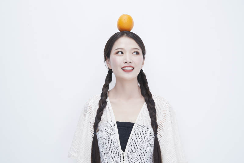 头顶橙子身穿镂空连衣裙的亚洲可爱少女人像图片